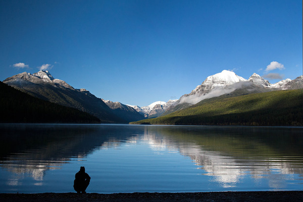 A visitor kneels along the shore of Bowman lake. Greg Lindstrom | Flathead Beacon
