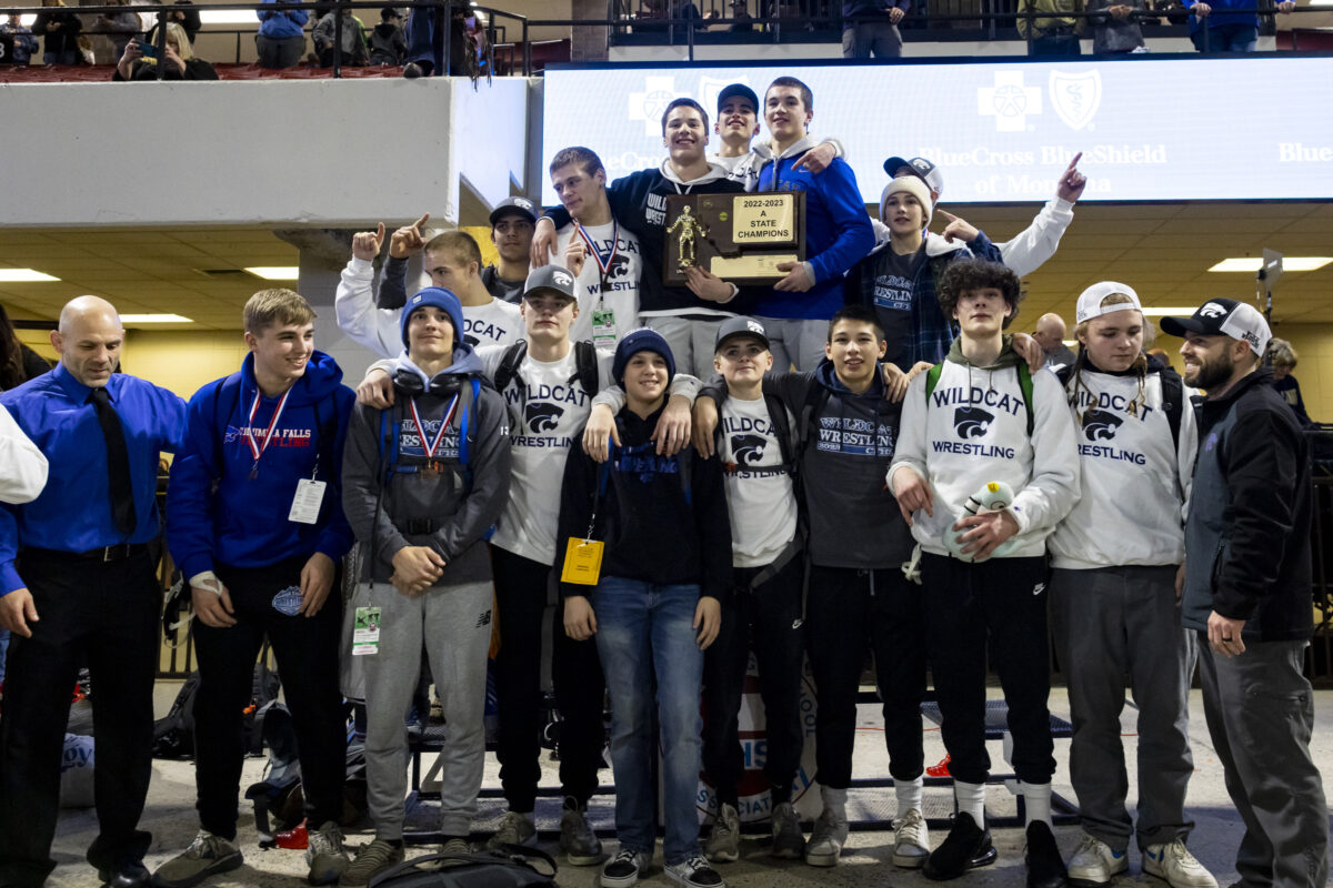 A photo showing the Columbia Falls Wrestling team arrayed in two rows, with the state championship trophy